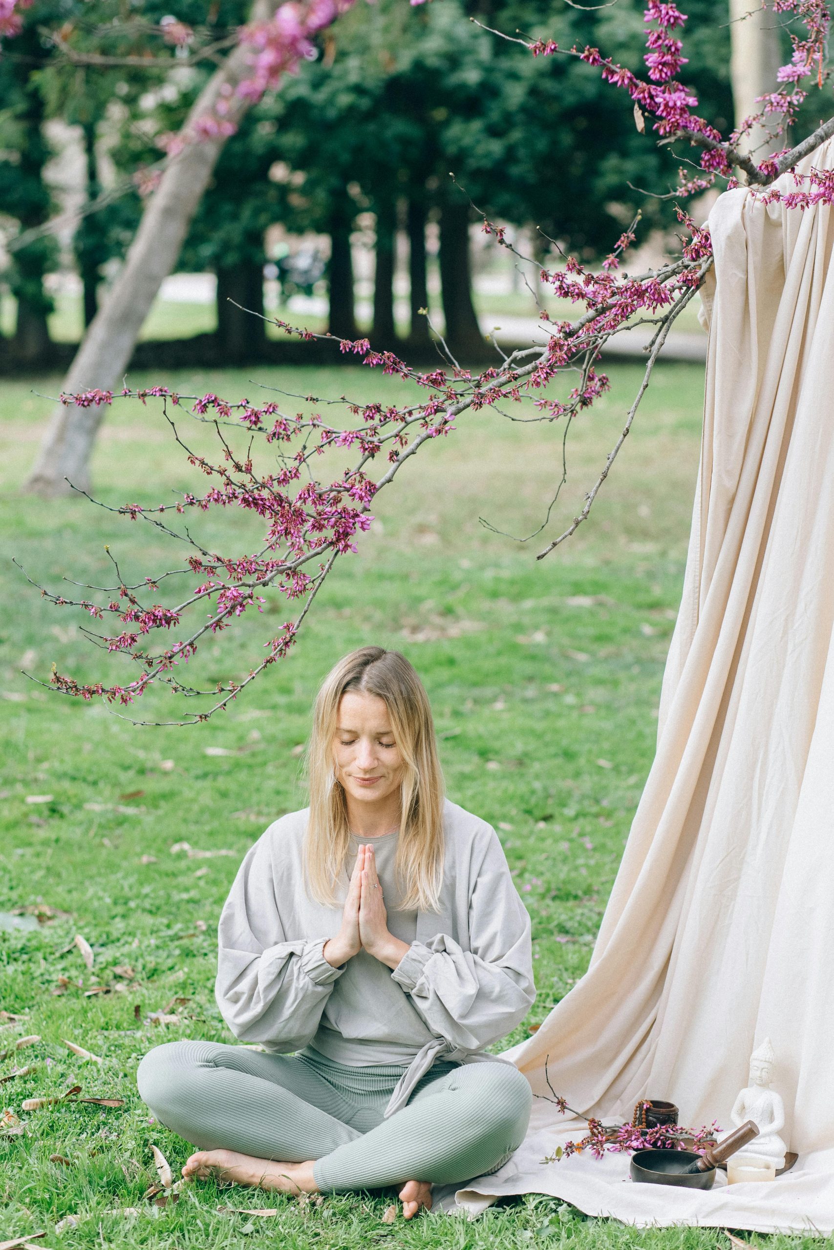 A woman meditating in a serene park with spring blooms, embracing nature's tranquility.